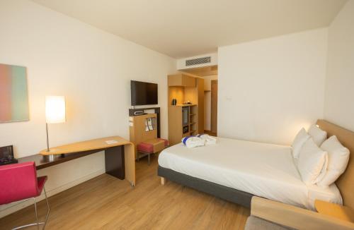 a small hotel room with a bed and a desk at Novotel Salerno Est Arechi in Salerno