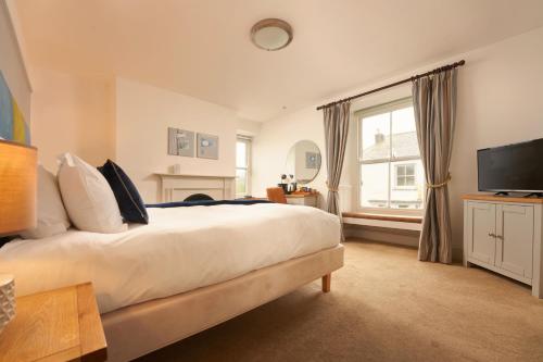 a bedroom with a large bed and a television at Rashleigh Arms in St Austell