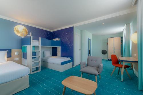 Grand Magic Hotel Marne La Vallée في ماني لو أونغر: غرفة مع غرفة نوم مع سرير ومكتب