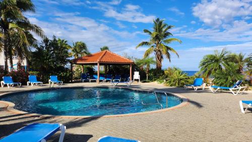 una piscina en un complejo con sillas y cenador en Ocean Teal Villa Marazul en Westpunt