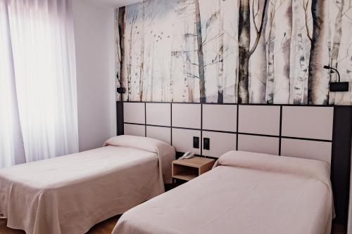 2 camas en una habitación con árboles en la pared en Hotel Casa Lorenzo, en Villarrobledo