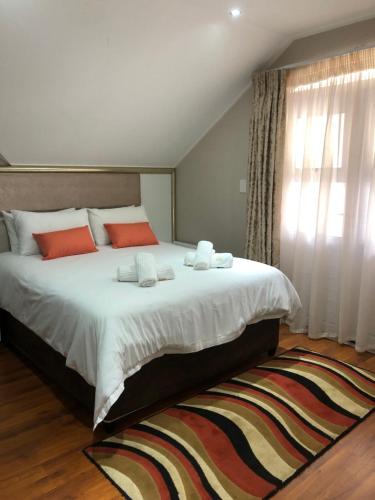 ein Schlafzimmer mit einem großen Bett mit weißer Bettwäsche und orangefarbenen Kissen in der Unterkunft CARIBBEAN POOL-SIDE VILLA 1148 in Port Edward
