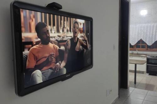 uma televisão com uma foto de um homem e uma mulher em Casa Inteira Próxima ao Centro / 4 Suítes. em Londrina