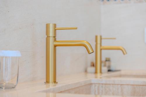 two gold faucets on a sink in a bathroom at La Posada del Mar in Denia
