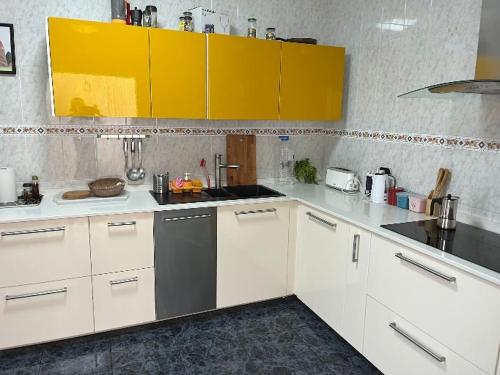 une cuisine avec des comptoirs blancs et des armoires jaunes dans l'établissement Sunset house, à Soo