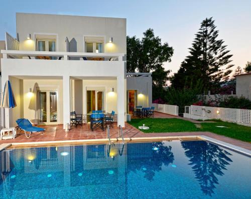 a villa with a swimming pool in front of a house at Oliv Apartments in Platanes