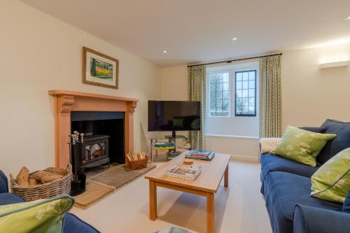 ein Wohnzimmer mit einem blauen Sofa und einem Couchtisch in der Unterkunft Charlton Down Cottage in Tetbury