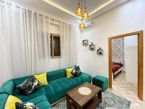 ein Wohnzimmer mit einem grünen Sofa und einem Tisch in der Unterkunft Appartement de Luxe in Kenitra