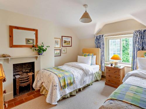 a bedroom with two beds and a fireplace at 3 Bed in Shaftesbury 92395 in Melbury Abbas