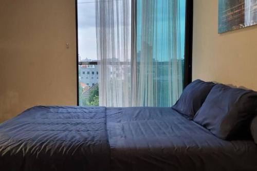 a bed in a bedroom with a large window at Apt Capitol Suite Senen 2 BR with Pool & Wifi in Jakarta