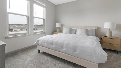 1 dormitorio blanco con 1 cama grande y 2 ventanas en Landing Modern Apartment with Amazing Amenities (ID1239X542), en Middleburg