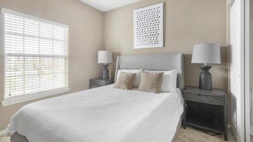 1 dormitorio con 1 cama blanca y 2 lámparas en Landing Modern Apartment with Amazing Amenities (ID1403X079), en Pinellas Park