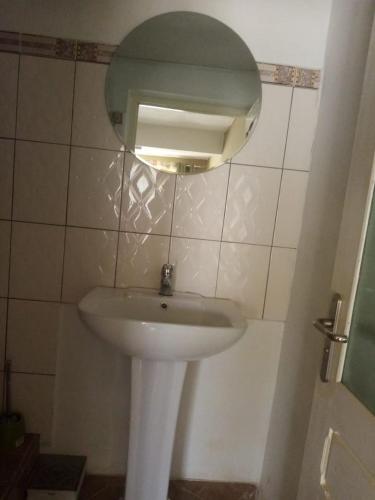 un lavandino bianco in un bagno con specchio di Tendry Guest House a Antananarivo