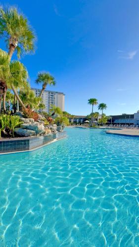a swimming pool with blue water and palm trees at Wyndham I-Drive Avanti Resort & Conference Center in Orlando
