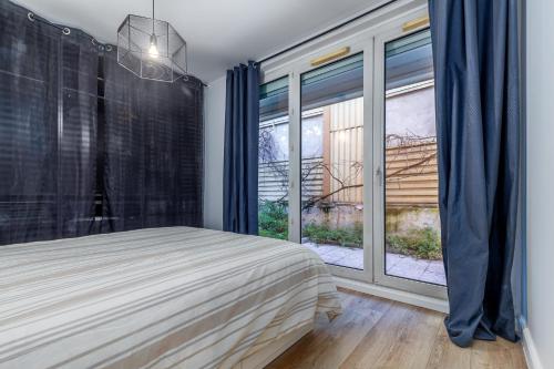 Un dormitorio con una cama y una ventana grande. en Oasis Urbaine for 8 near to Paris, en Villejuif