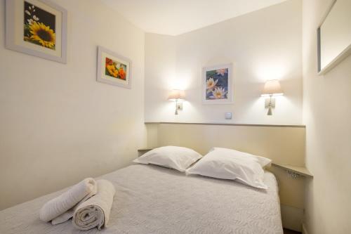 ein Schlafzimmer mit einem Bett mit weißen Laken und Kissen in der Unterkunft Sur la mer in Cannes