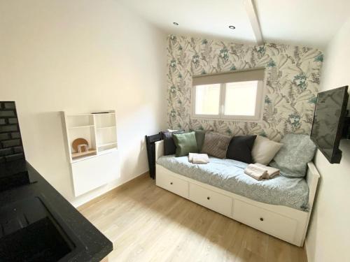 una pequeña sala de estar con sofá y ventana en Maisonnette Cosy au calme en Gentilly