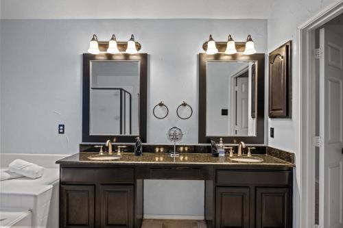 a bathroom with two sinks and two mirrors at Heated Pool PoolTable HotTub Sleeps 16 Renovated in McKinney