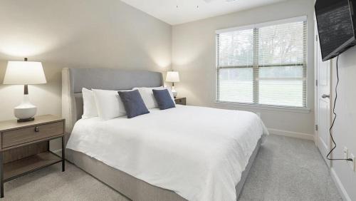 - une chambre blanche avec un grand lit et une fenêtre dans l'établissement Landing Modern Apartment with Amazing Amenities (ID1012X377), à Wake Forest