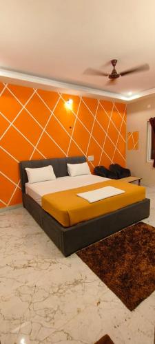 ein Schlafzimmer mit einem Bett mit einer orangefarbenen Wand in der Unterkunft Silver Oak stay in Yercaud