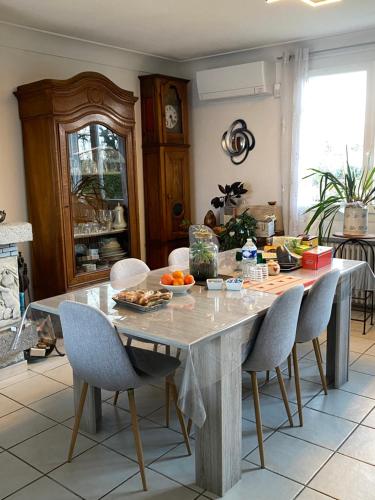 une cuisine avec une table, des chaises et de la nourriture. dans l'établissement Chambre privée dans maison + petit déjeuner offert, à Saint-Priest