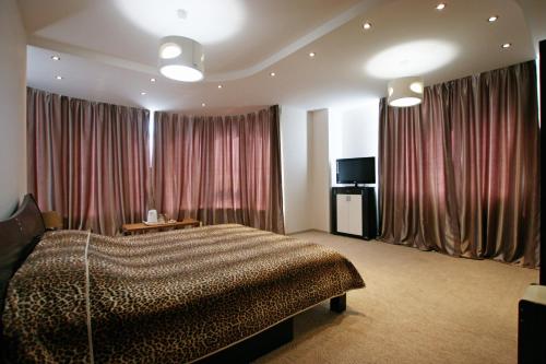 a bedroom with a bed and curtains and a television at Mini hotel in Observatorniy in Odesa