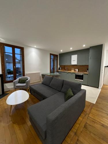 ein Wohnzimmer mit einem grauen Sofa und einem Tisch in der Unterkunft Appartement cosy à Choisy-Le-Roi in Choisy-le-Roi