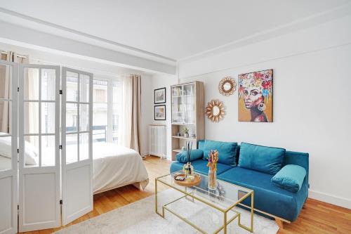 - un salon avec un canapé bleu et un lit dans l'établissement Parisian Charm Porte Maillot, à Paris