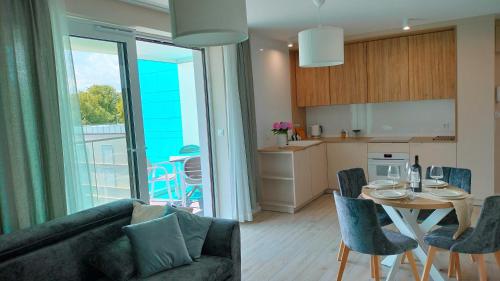 a living room with a couch and a table with chairs at Cicha Przystań Apartamenty WhiteBlue sauna&fitness&parking in Kołobrzeg