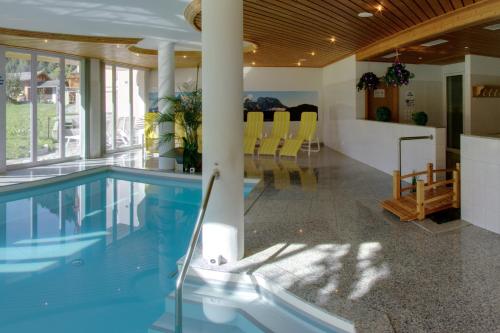 a swimming pool in a house with yellow chairs at Aktiv- und Genusshotel Alpenblick in Fiesch