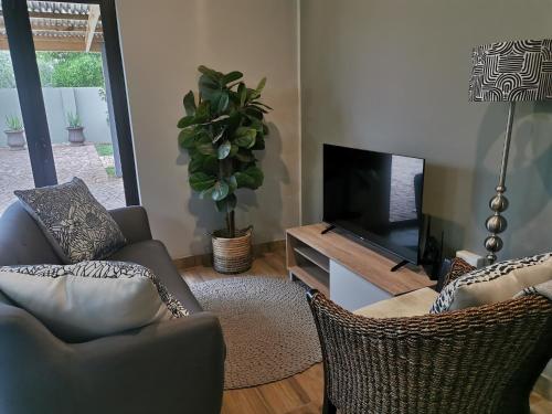 uma sala de estar com duas cadeiras e uma televisão em Lekaja em Oudtshoorn