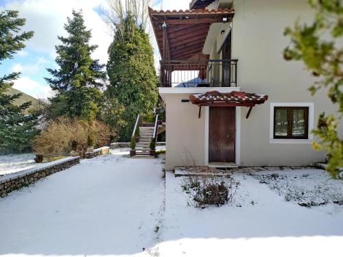 a house with a snow covered yard with a door at Escape Suite @ Villa Arcadia in Vlakhérna
