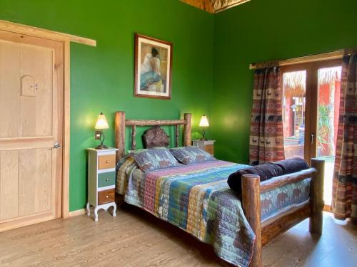 een slaapkamer met groene muren en een bed met een houten frame bij Finca el Péndulo in Tepatitlán de Morelos