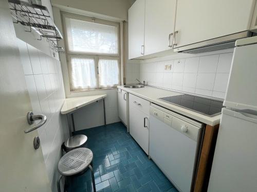 a small kitchen with white cabinets and a blue floor at Villa Ninfea in Grado