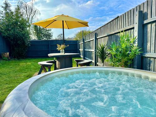 a hot tub in a yard with an umbrella at Large Four Bedroom - With Hot Tub and Parking - Sleeps 8 in Poole