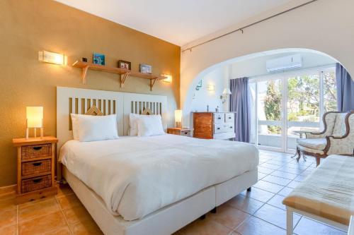 a bedroom with a large white bed and a chair at Cozy 2 BDR W/Balcony in Vale do Lobo by LovelyStay in Vale do Lobo