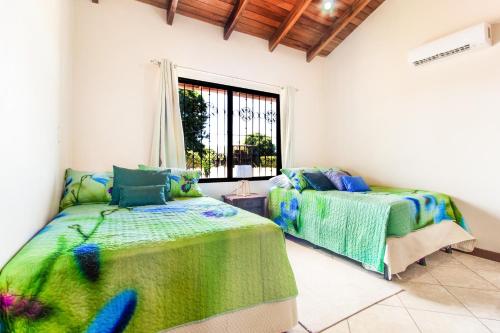 1 dormitorio con 2 camas y ventana en Villa Roble Alto en Guanacaste