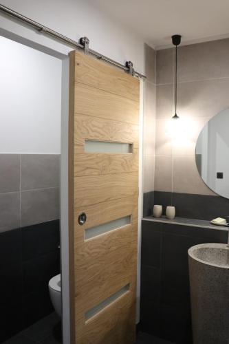 a bathroom with a wooden door next to a toilet at Le Clos 1855 in Saint-Laurent-des-Bâtons