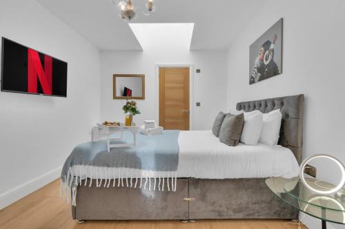 homely - West London Apartments Putney في لندن: غرفة نوم بسرير كبير وطاولة