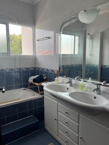 uma casa de banho com um lavatório, uma banheira e um espelho. em Populo Beach Villa em Livramento