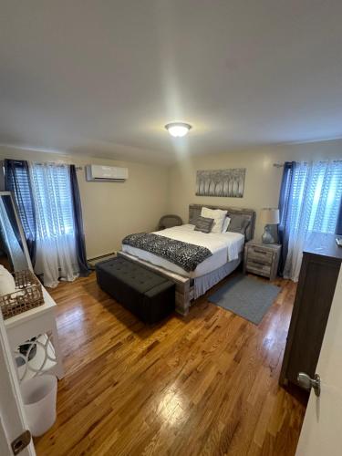 a bedroom with a bed and wooden floors and windows at Chic modern bedroom 5 mins from JFK in Locust Manor