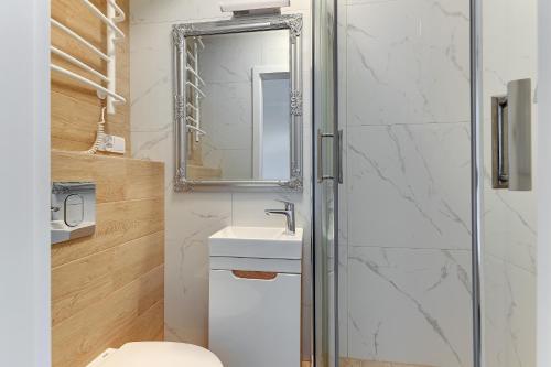 a bathroom with a toilet and a sink and a mirror at Grobla Centre 4 by Grand Apartments in Gdańsk