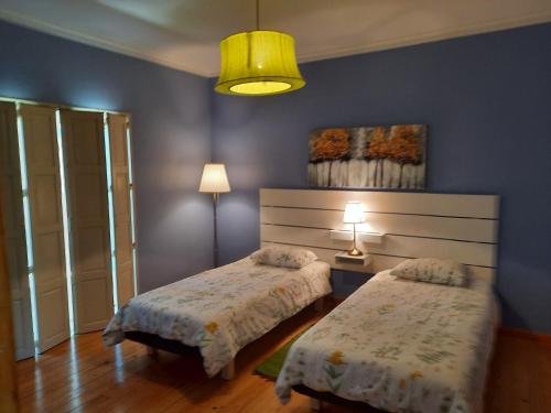 a bedroom with two beds and a yellow light at Casa Azul in Vila de Rei