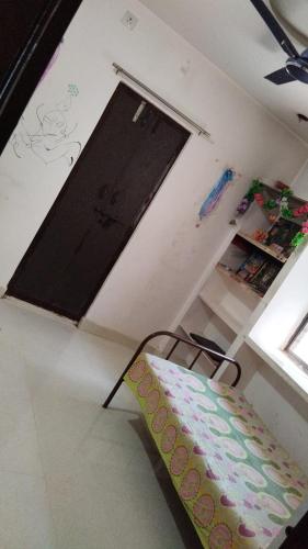 Zimmer mit einem Stuhl, einer Tür und einem Regal in der Unterkunft Divyashray in Hyderabad