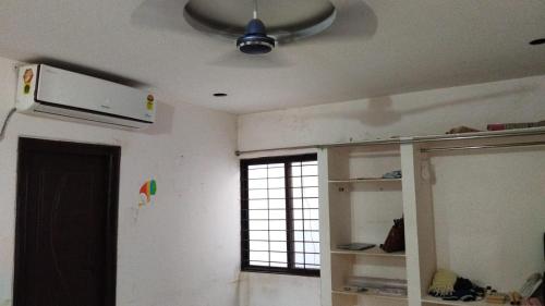 salon z wentylatorem sufitowym i oknem w obiekcie Divyashray w mieście Hajdarabad