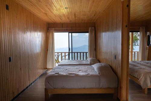 a bedroom with two beds and a balcony at Cabañas Casa de Niebla in Pluma Hidalgo