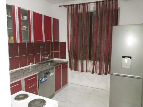 a kitchen with red cabinets and a stainless steel refrigerator at Stefanelo in Ulcinj