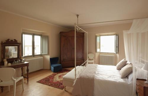 a bedroom with a bed and a desk and windows at B&B Palazzo Mattei in Novafeltria
