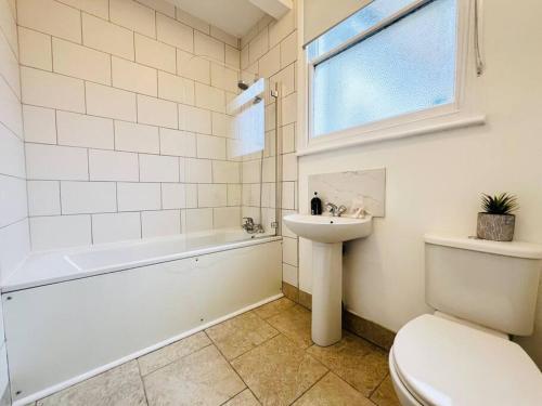 a bathroom with a sink and a tub and a toilet at Crouch End Garden Apartment! in London