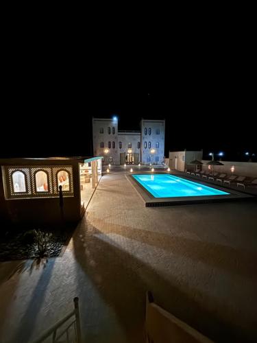 a swimming pool in front of a building at night at Dar Morocco in Merzouga
